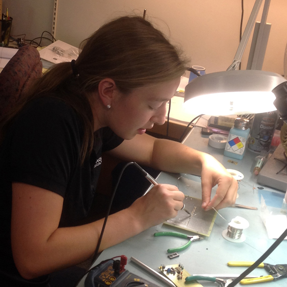 intern soldering motherboard in manufacturing facility