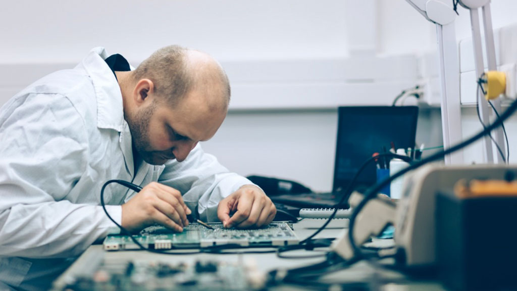 Technician fixing motherboard by soldering